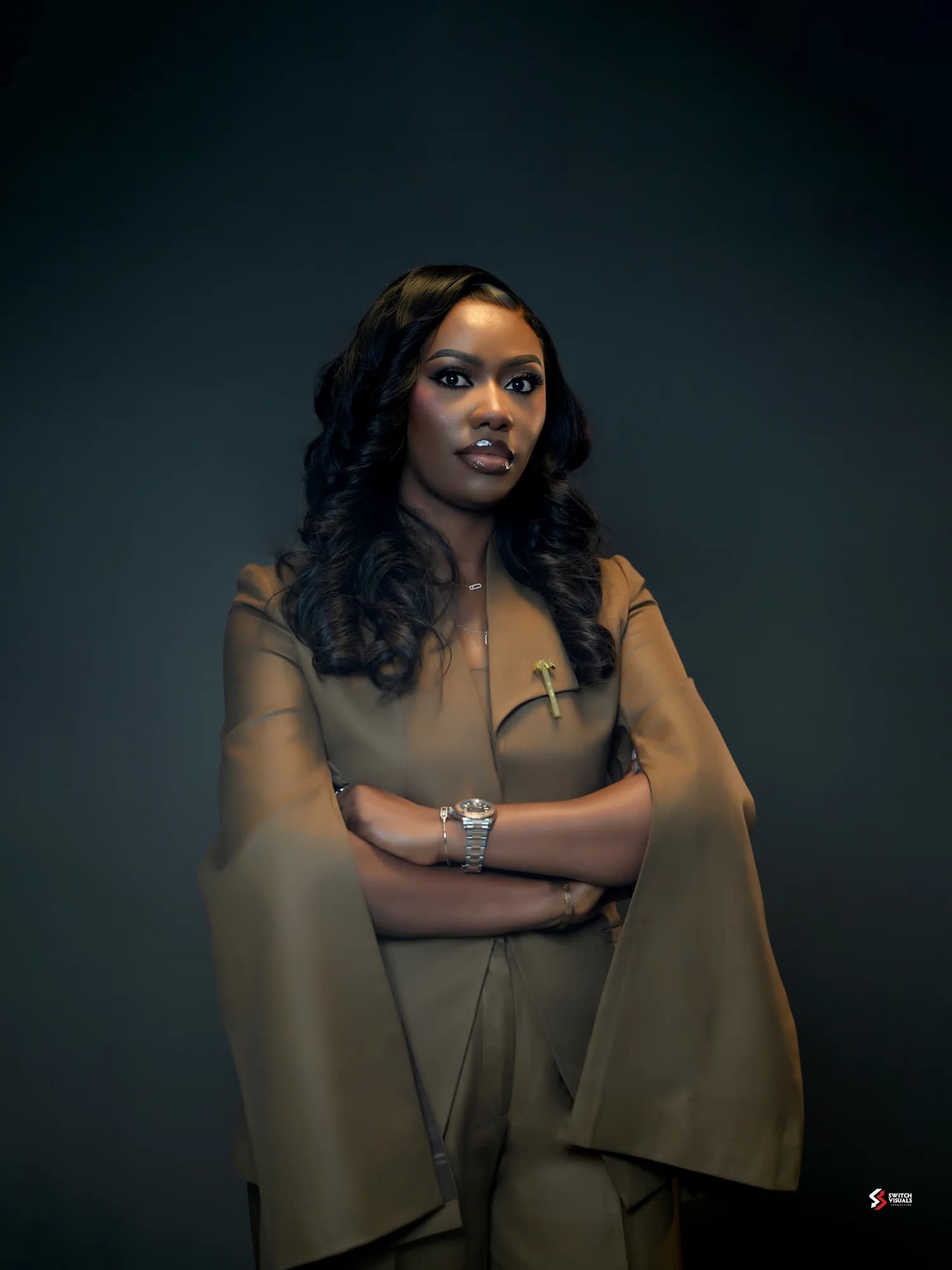 Damilola Osikoya with her arms folded, wearing a tailored cape-sleeve outfit.