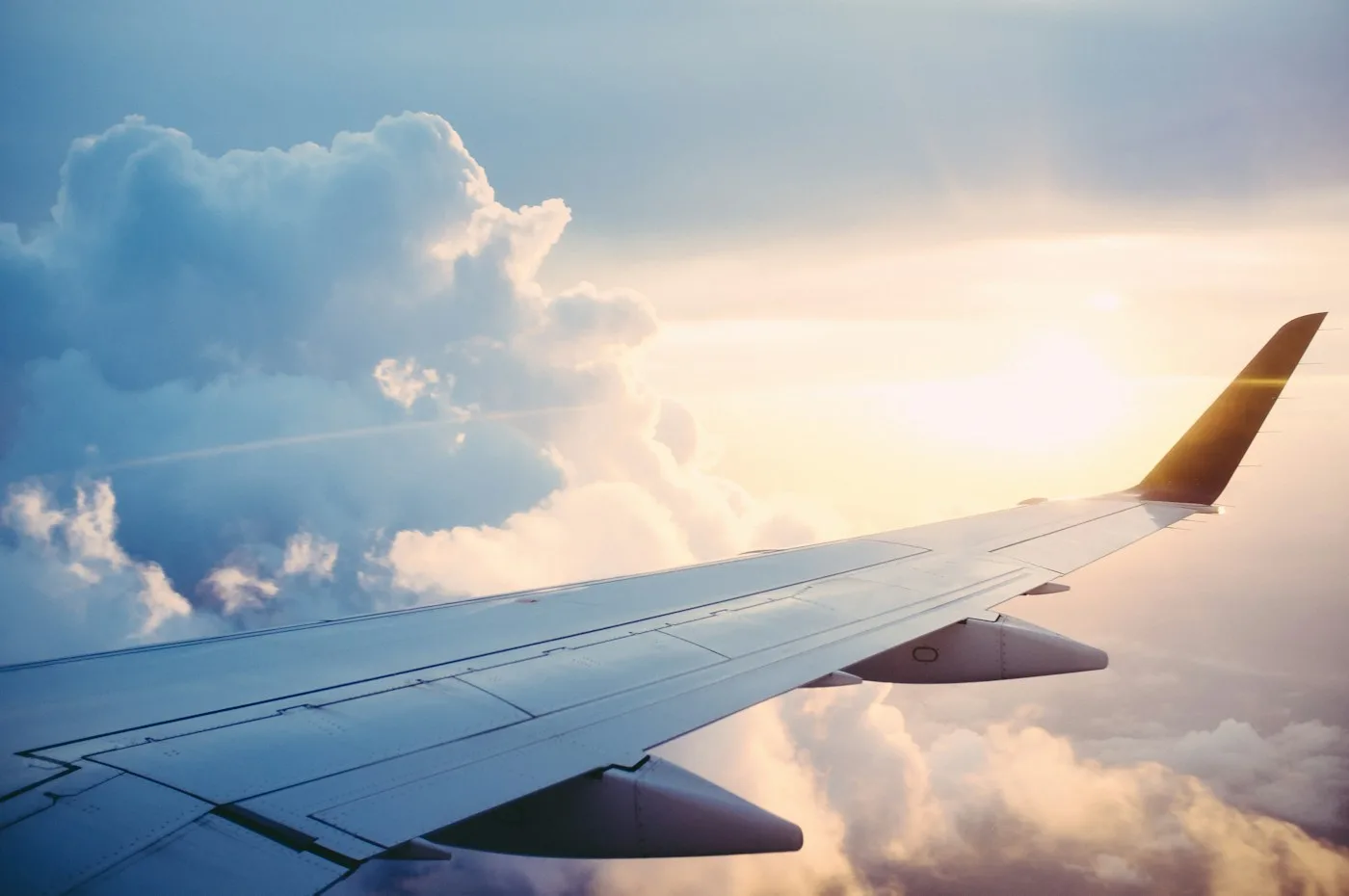 An aircraft wing above the clouds at sunset.